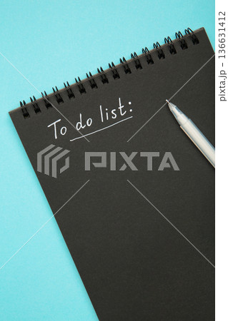 To do list on black notebook with white pen on blue background. To do list on black notebook with white pen on blue background. 136631412