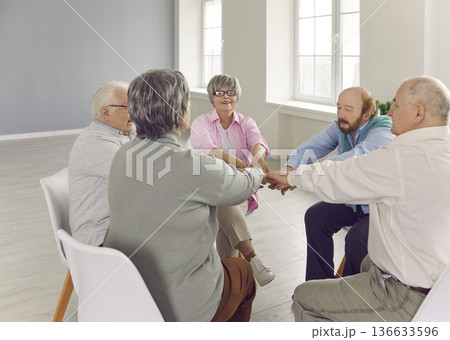 Senior people talking on therapy session at nursing home holding hands together. 136633596