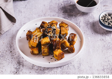 Roasted tofu cubes in garlic soy sauce with sesame seeds on a plate on the table Roasted tofu cubes in garlic soy sauce with sesame seeds on a plate on the table 136633858