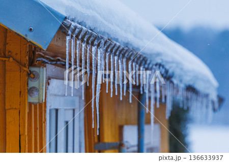 Icicles on the roof of the house. Danger of falling 136633937