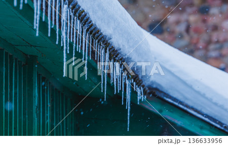 Icicles on the roof of the house. Danger of falling Icicles on the roof of the house. Danger of falling 136633956