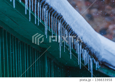 Icicles on the roof of the house. Danger of falling Icicles on the roof of the house. Danger of falling 136633958