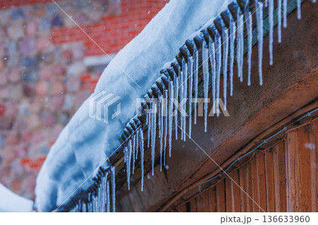 Icicles on the roof of the house. Danger of falling Icicles on the roof of the house. Danger of falling 136633960