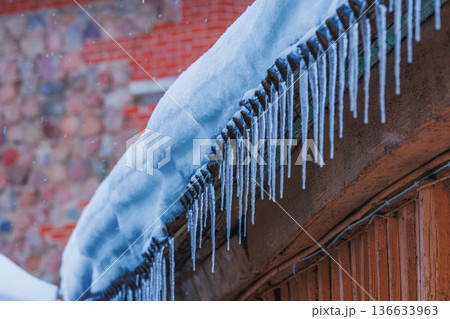 Icicles on the roof of the house. Danger of falling Icicles on the roof of the house. Danger of falling 136633963