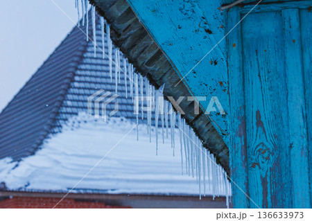 Icicles on the roof of the house. Danger of falling Icicles on the roof of the house. Danger of falling 136633973
