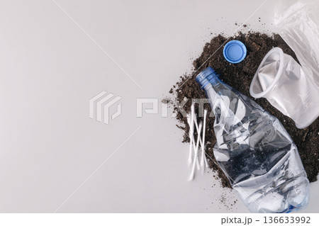 Plastic waste polluting soil with disposable items 136633992