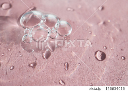 Clear bubbles and water drops creating organic patterns on pink surface 136634016
