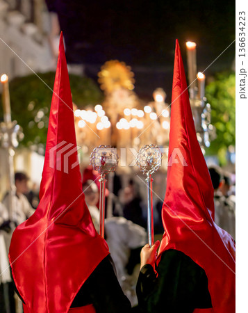 Back view of two nazarenos in red hoods with silver scepters 136634223