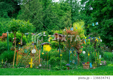 Bright creative garden with birdhouses, flowers and handmade decorations. Lush greenery and vibrant colors in a cozy backyard setting. 136634741