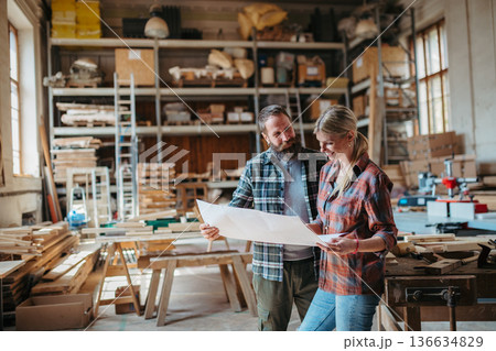Two carpenters man and woman talking about design of products. Small business concept. Two carpenters man and woman talking about design of products. Small business concept. 136634829