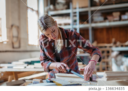 Female carpenter working on her product in carpentry workshop. Female carpenter working on her product in carpentry workshop. 136634835