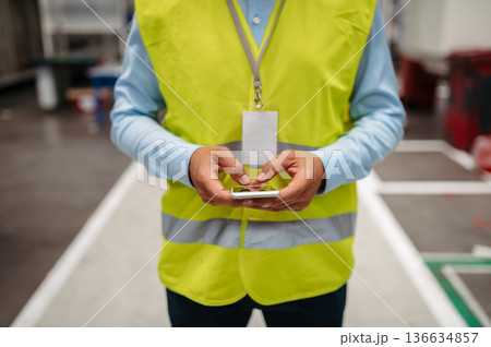 Close-up of female hands in factory using smartphone. Copy space. 136634857