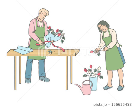 Male florist tying ribbon around bouquet at table and female florist holding rose Male florist tying ribbon around bouquet at table and female florist holding rose 136635458