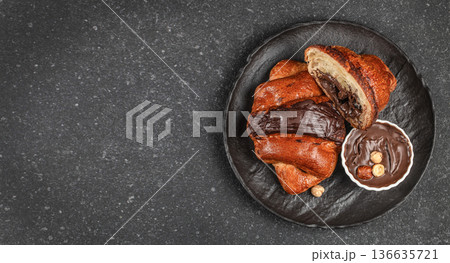 Chocolate filled croissants with creamy hazelnut spread on black plate 136635721