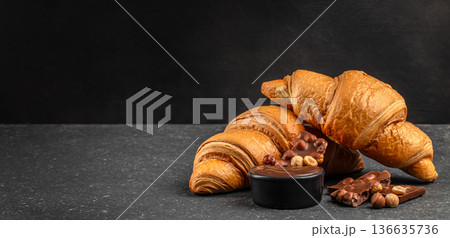 Fresh butter croissants with chocolate cream and hazelnut on dark background Fresh butter croissants with chocolate cream and hazelnut on dark background 136635736