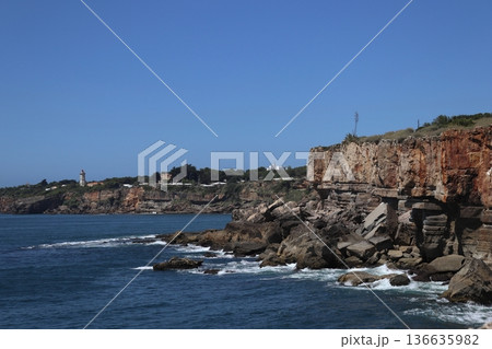 Jagged limestone cliffs of Cascais with lighthouse in the distance Jagged limestone cliffs of Cascais with lighthouse in the distance 136635982