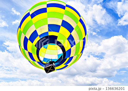 Colorful hot air balloon flying over blue sky with white clouds 136636201