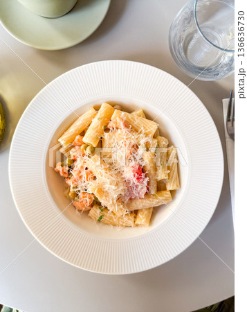 Overhead view of pasta with vegetables and grated cheese on white plate. Culinary scene symbolizing gourmet cuisine, nutrition and lifestyle dining. 136636730