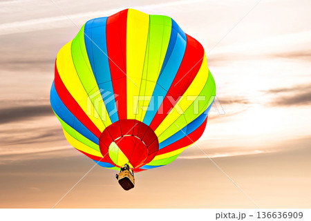 Colorful hot air balloon flying under orange sunset sky Colorful hot air balloon flying under orange sunset sky 136636909