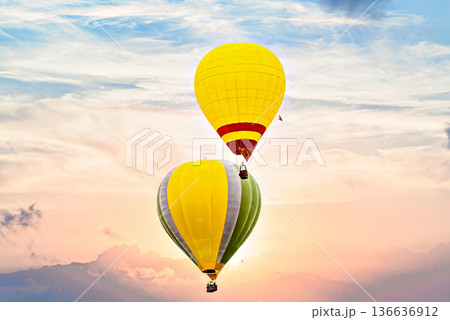 Colorful hot air balloon flying under orange sunset sky 136636912