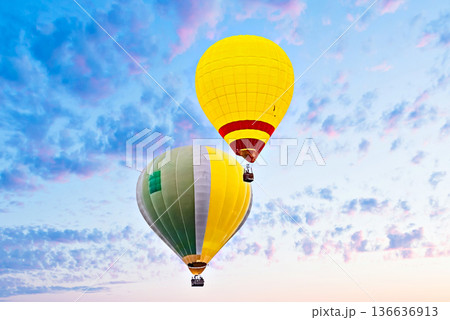 Colorful hot air balloon flying under orange sunset sky Colorful hot air balloon flying under orange sunset sky 136636913