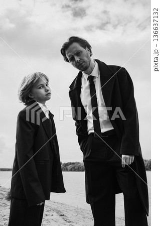 Serious father and daughter looking at camera outdoors, black and white Serious father and daughter looking at camera outdoors, black and white 136637132