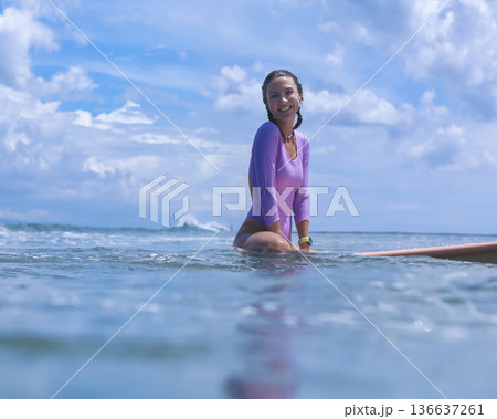 Lively Woman In Violet Clothing Calmly Reclining On Her Surfboard At Dawn Lively Woman In Violet Clothing Calmly Reclining On Her Surfboard At Dawn 136637261