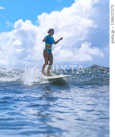 Contented Woman Surfing On Her Longboard Under Golden Sunlight In Ocean Contented Woman Surfing On Her Longboard Under Golden Sunlight In Ocean 136637272