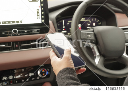 運転席でスマホを操作している男性の手元 運転席でスマホを操作している男性の手元 136638366