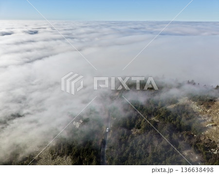 Vivid Aerial Perspective Revealing Swirling Fog Intertwining With Forested Slopes And Textured Terrain Vivid Aerial Perspective Revealing Swirling Fog Intertwining With Forested Slopes And Textured Terrain 136638498