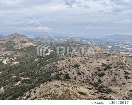 Trail Runner Navigating Rugged Ridge With Sparse Vegetation And Distant Cityscape On Horizon 136638617