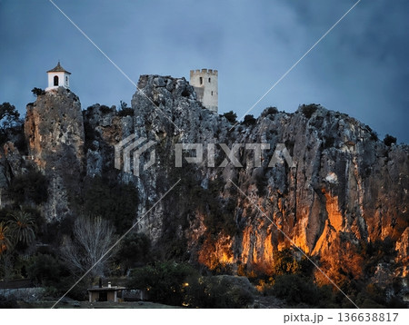 Sturdy Historic Castle Perched High On Rugged Cliff With Evening Lighting And Village Backdrop Sturdy Historic Castle Perched High On Rugged Cliff With Evening Lighting And Village Backdrop 136638817