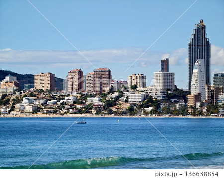Peaceful Fishing Skiff Gently Glides On Turquoise Waters Beneath Distant Skyline And Solitary Tower 136638854