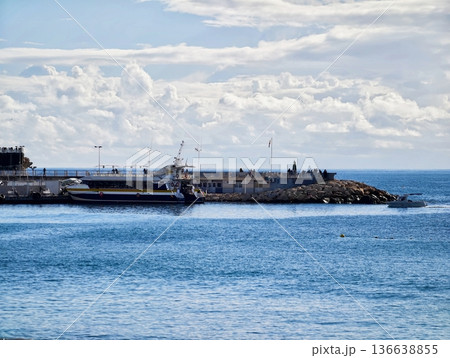 Tranquil Seascape With Lighthouse, Calm Harbor Surroundings Featuring Distant Lighthouse And Patrol Boat 136638855
