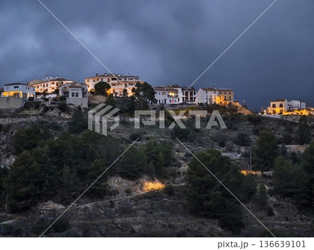 Nighttime Village Scene, Small Town Homes Glow Under Ominous Sky With Streetlights Illuminating Ridge Nighttime Village Scene, Small Town Homes Glow Under Ominous Sky With Streetlights Illuminating Ridge 136639101