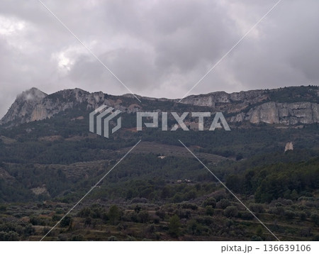 Gloomy Mountain Chain Cloaked In Heavy Fog Towers Over Thriving Forest Landscapes Perfect For Adventure 136639106