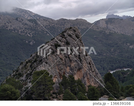 Vertical Rocky Formation With Pines, Rugged Stone Spire Emerges Amid Pinecovered Hills And Stormy Sky 136639108