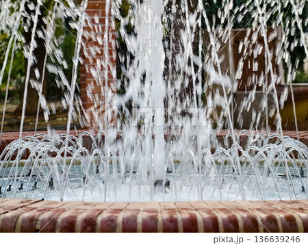 Sunny Fountain Scene, Tranquil Urban Water Feature With Flowing Jets And Sunlight Shimmering On Surface Sunny Fountain Scene, Tranquil Urban Water Feature With Flowing Jets And Sunlight Shimmering On Surface 136639246