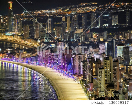 Bright Coastal Night Scene, Vivid Nighttime Image Of Illuminated Shoreline And Lively Beach Party 136639517
