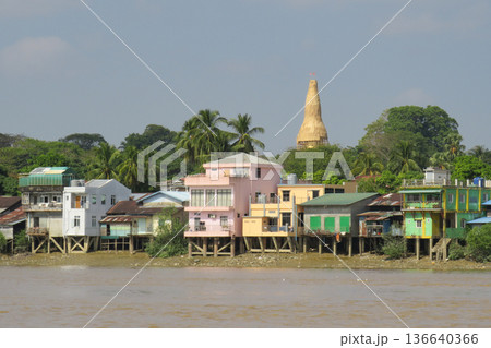 Houses on stilts and gold pagoda on a riverbank in Myanmar Houses on stilts and gold pagoda on a riverbank in Myanmar 136640366