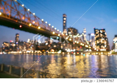 Soft colorful lights from the Queensboro Bridge and Manhattan skyline blur together in a dreamy bokeh scene. Reflections shimmer across the East River, creating an artistic and atmospheric city view. Soft colorful lights from the Queensboro Bridge and Manhattan skyline blur together in a dreamy bokeh scene. Reflections shimmer across the East River, creating an artistic and atmospheric city view. 136640767