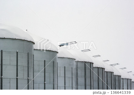 Monochrome of steel grain bins covered with snow after snowfall. Monochrome of steel grain bins covered with snow after snowfall. 136641339