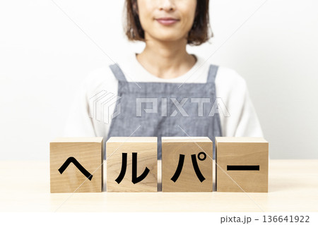 「ヘルパー」と書かれたブロックとエプロン姿の女性 「ヘルパー」と書かれたブロックとエプロン姿の女性 136641922