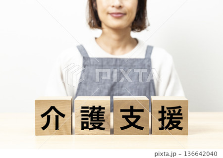 「介護支援」と書かれたブロックとエプロン姿の女性 136642040