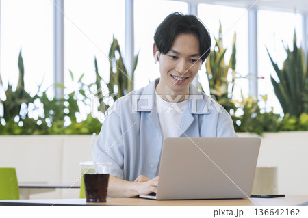 ノートパソコンで作業をするイヤホンをした30代の男性 136642162