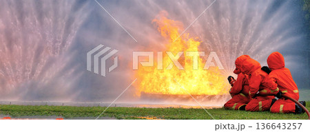 Firefighter Rescue training in fire fighting extinguisher. Firefighter fighting with flame using fire hose chemical water foam spray engine. Fireman wear hard hat, safety suit uniform for protection 136643257