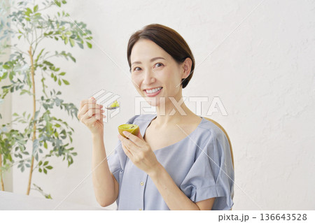 リビングでキウイフルーツを食べる女性 リビングでキウイフルーツを食べる女性 136643528