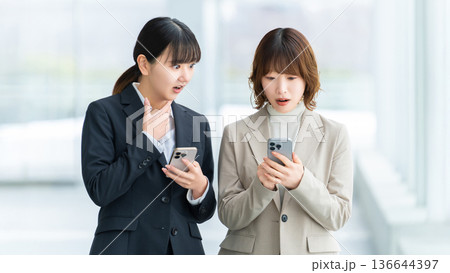 スマートフォンを見て驚く2人の女性・ビジネスウーマン スマートフォンを見て驚く2人の女性・ビジネスウーマン 136644397