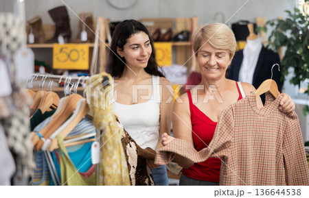Two women choosing clothes on sale in a store Two women choosing clothes on sale in a store 136644538