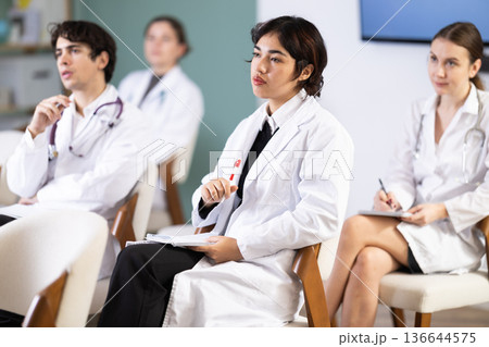 Malaysian woman sitting in chair in auditorium and listening attentively to lecture 136644575